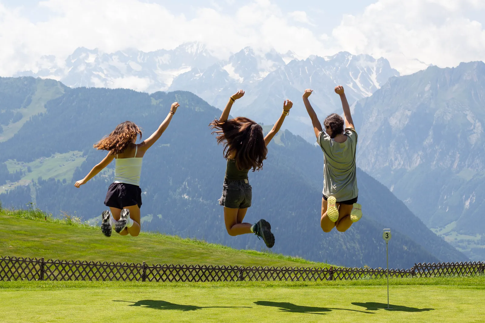 Three campers jumping on the grass above Verbier
