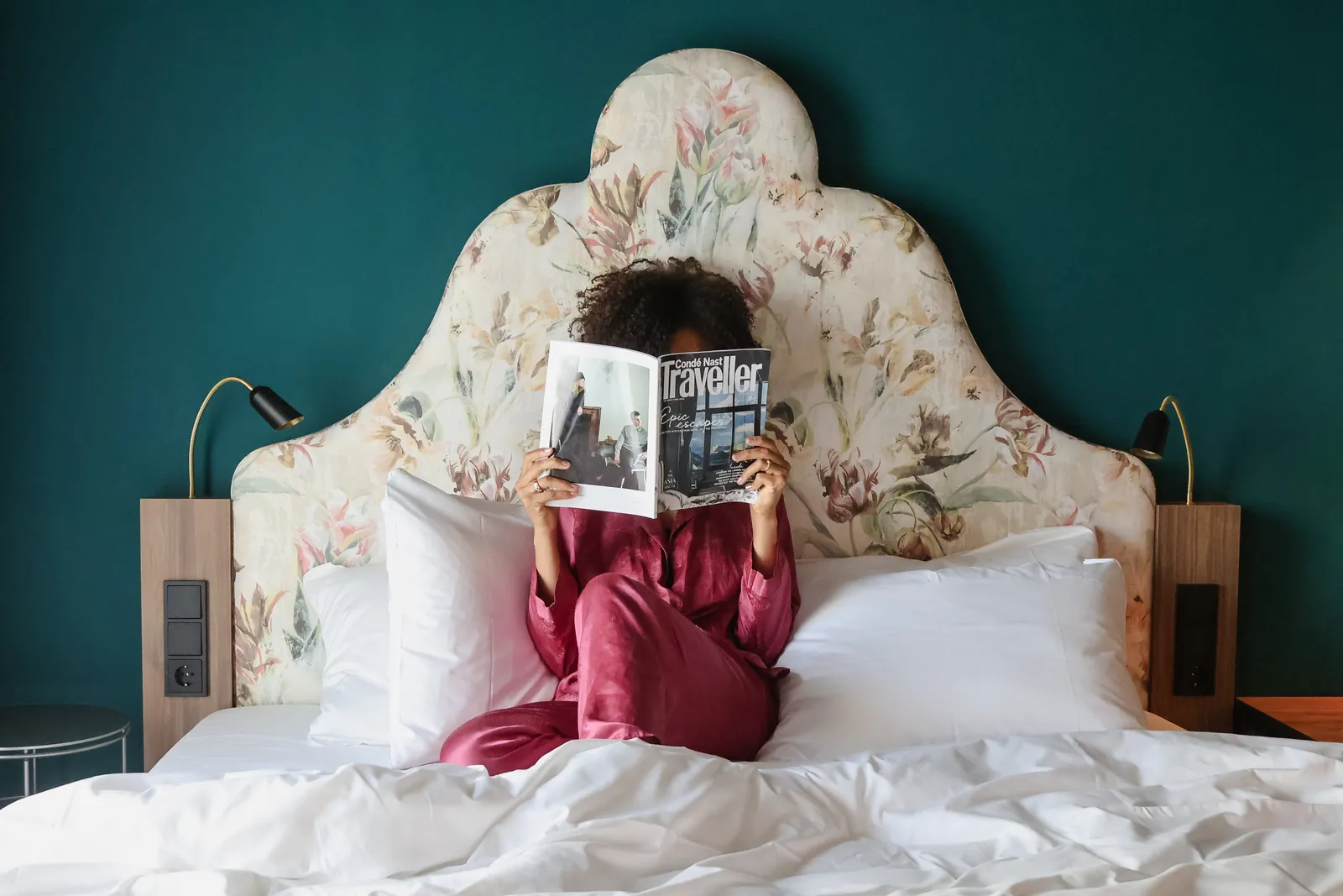 A guest reading a magazine in bed at Me and All Hotels